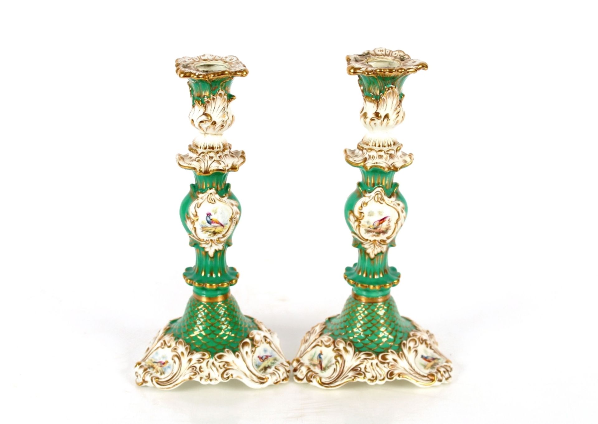 A pair of Rockingham style candlesticks with bird and floral decoration, heightened in gilt on green