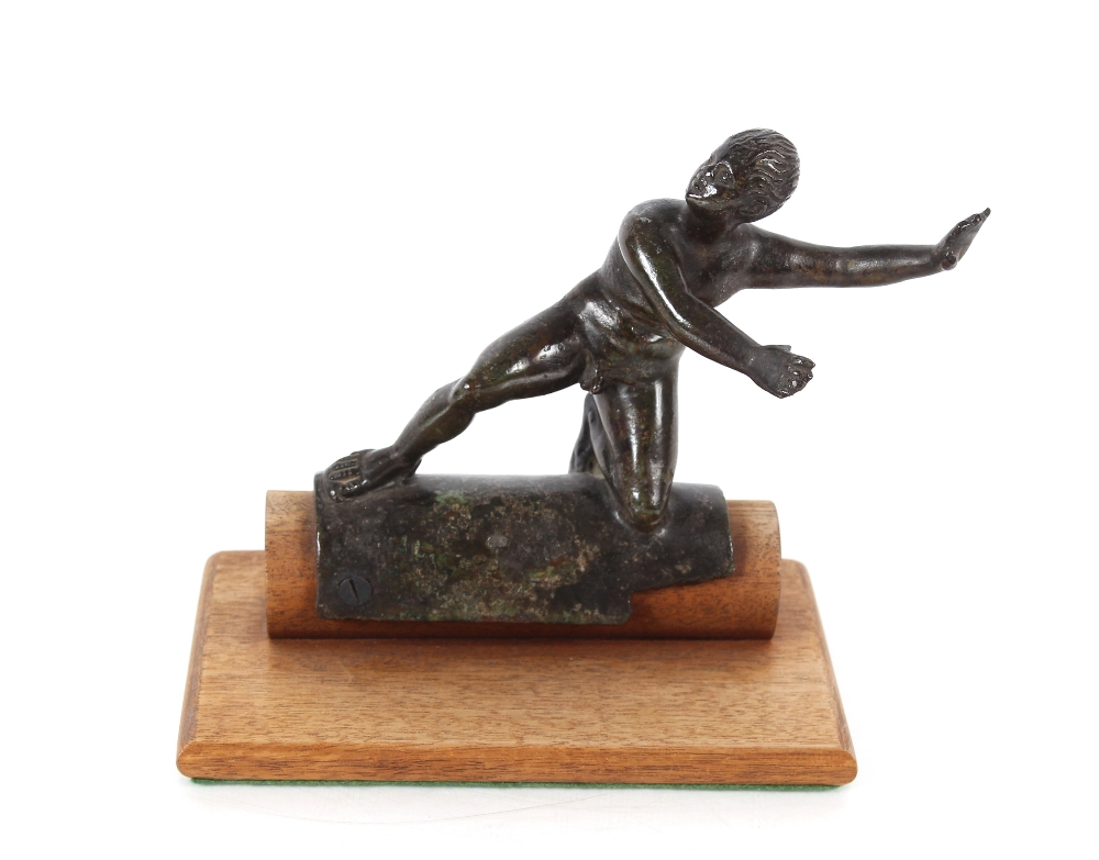 A bronze figure of a naked man balanced on a log, set on a wooden base, 17cm high