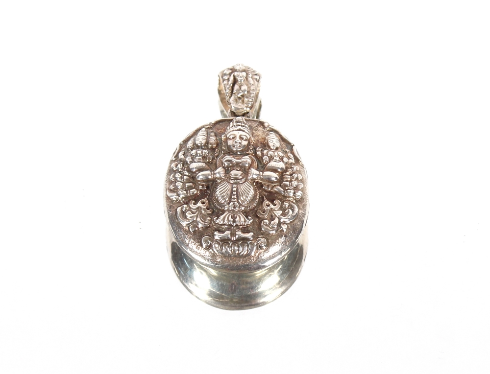 A large white metal Asian locket, having raised decoration of deities and flowers