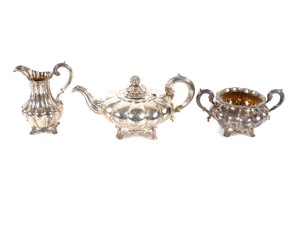 A Victorian three piece silver tea set of melon shape, having scrolled handles and raised on foliate