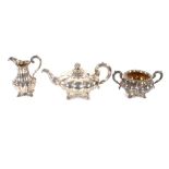 A Victorian three piece silver tea set of melon shape, having scrolled handles and raised on foliate