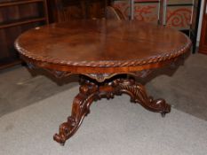 A 19th Century walnut snap top pedestal supper table, the radially veneered top with a gadrooned