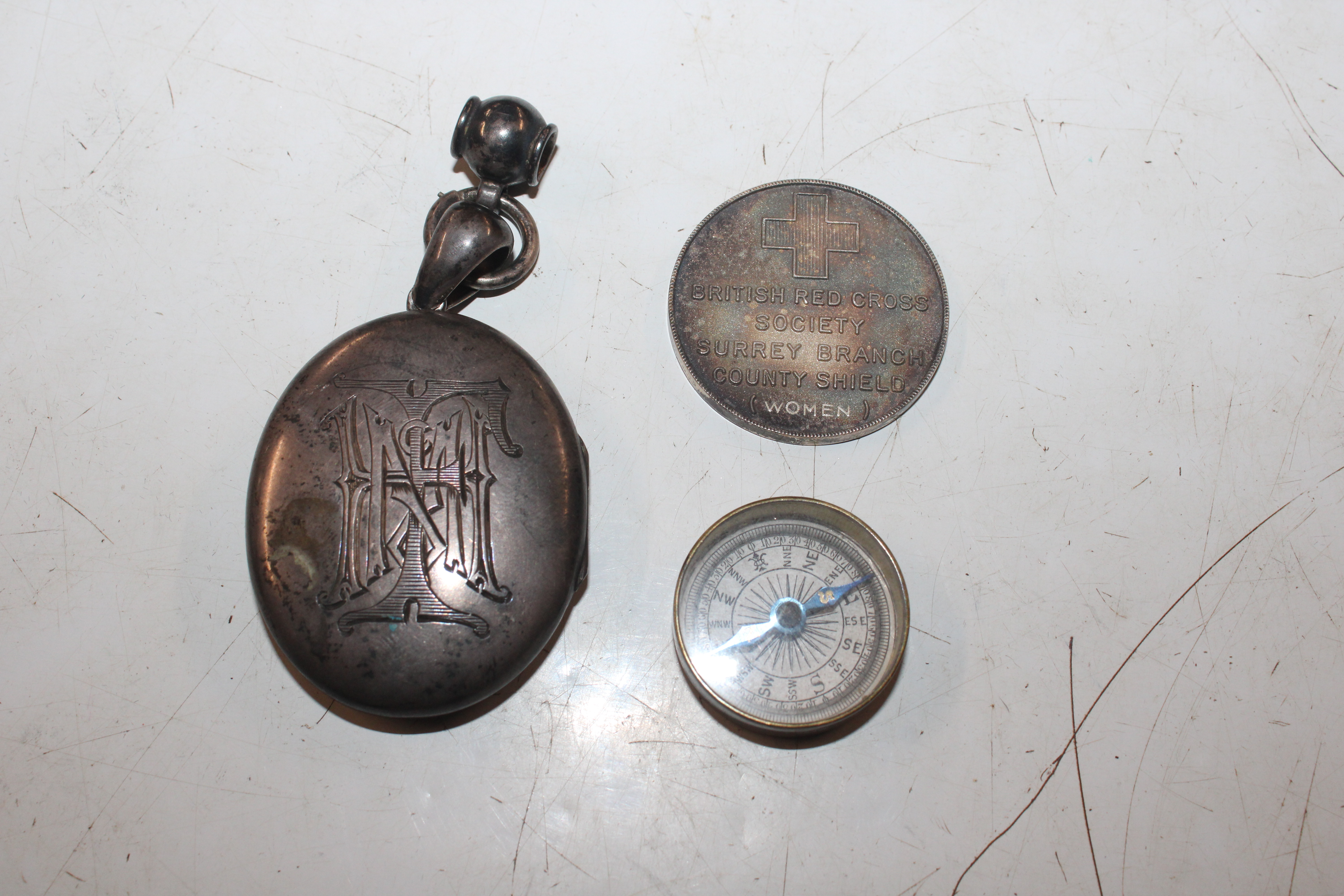 A white metal locket; a silver British Red Cross S