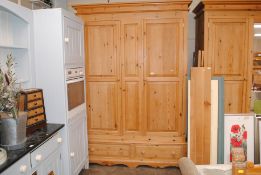 A large stripped pine wardrobe enclosed by fielded