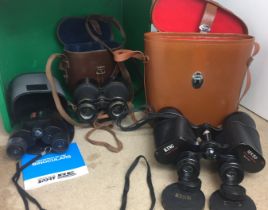 Green plastic box containing three pairs of binoculars - King 12x50 with leather case,