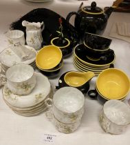 Two part tea services - black and yellow and yellow floral patterned,