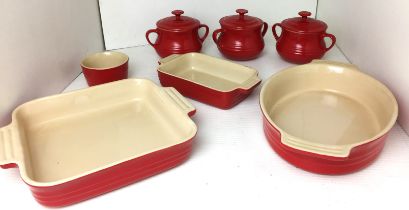 Grey plastic box containing seven pieces of Le Creuset ceramic oven to tableware in red including