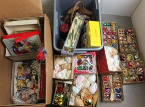 Two boxes containing Christmas decorations, pine cones, candles,