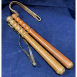 Two brown stained wooden truncheons with leather straps,