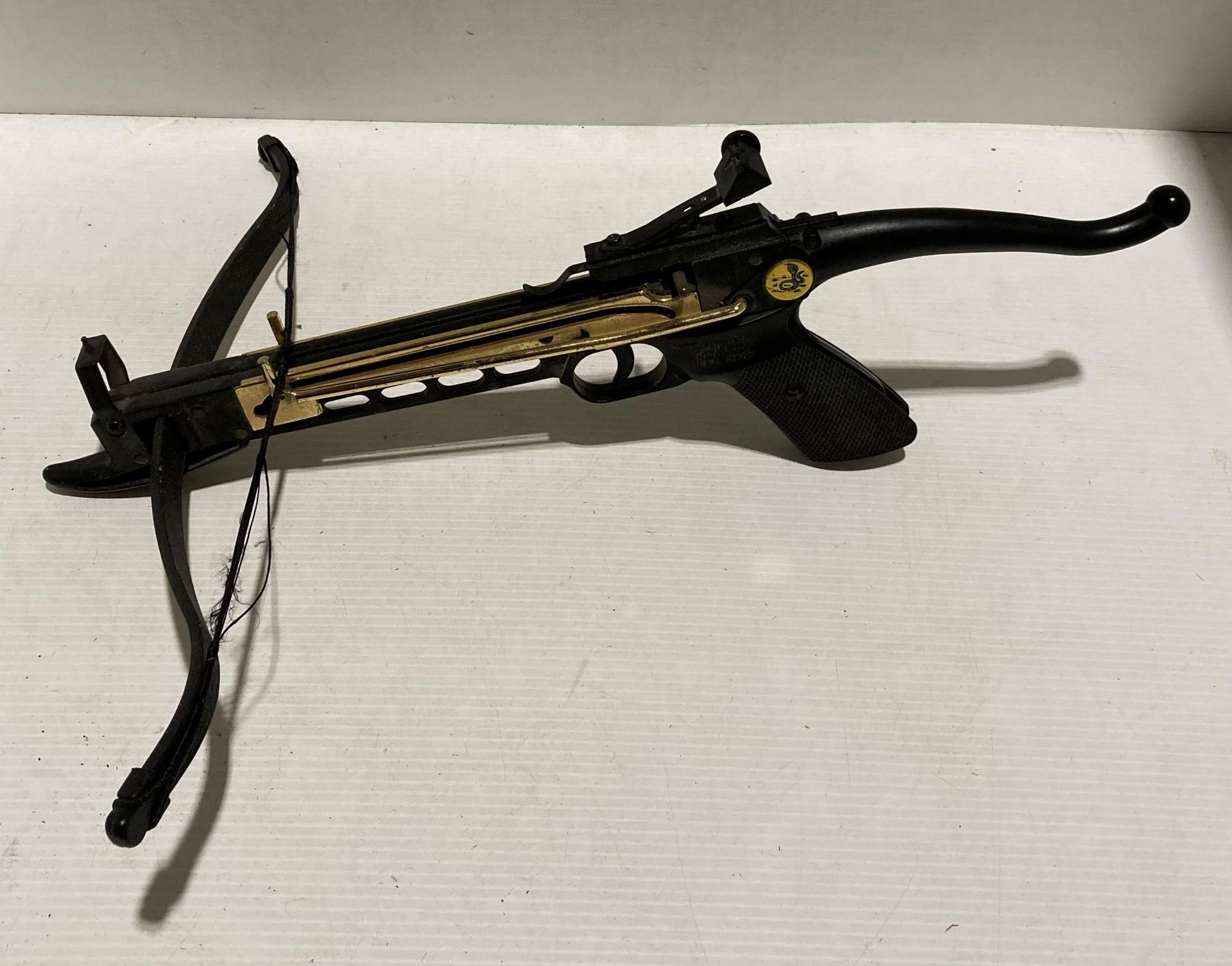 Black and gold coloured self-cocking hand pistol crossbow,