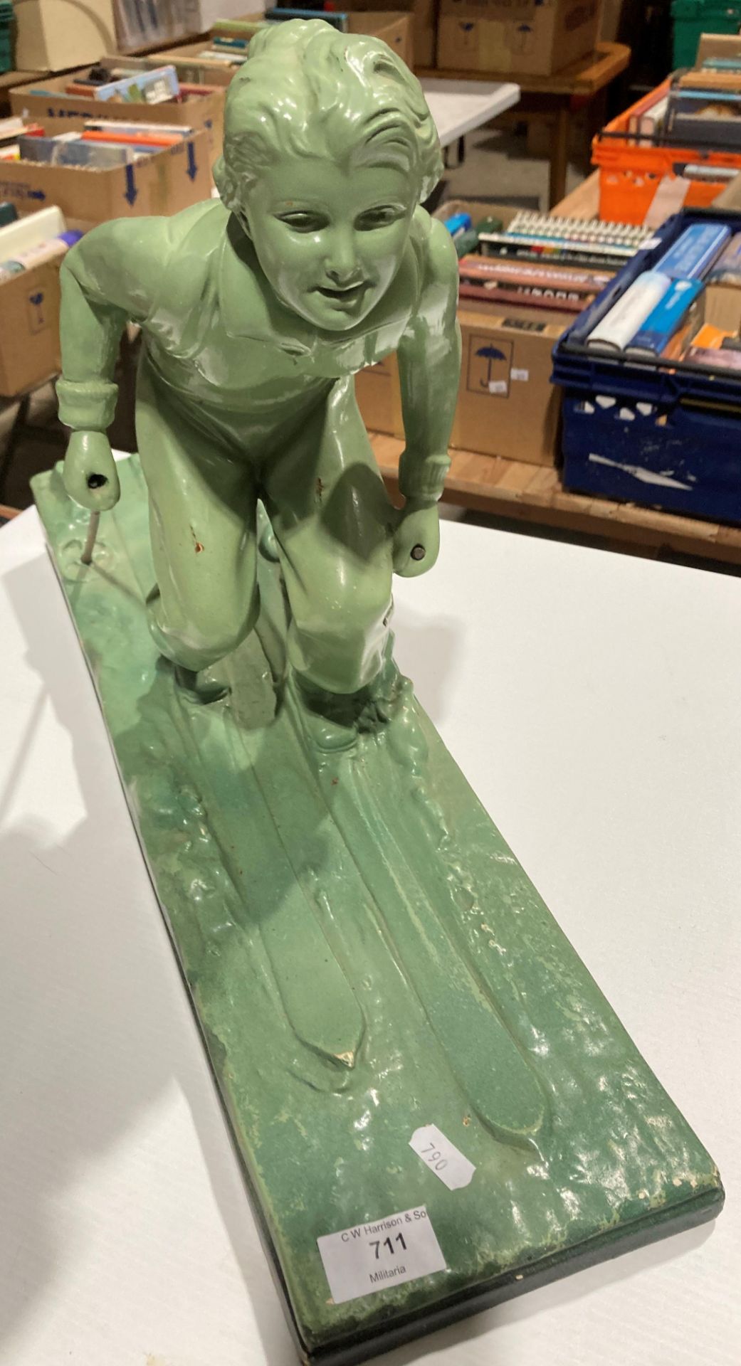 A green plaster sculpture of a female skier reg no: OP 428 RD 833044 on base (one stick broken),