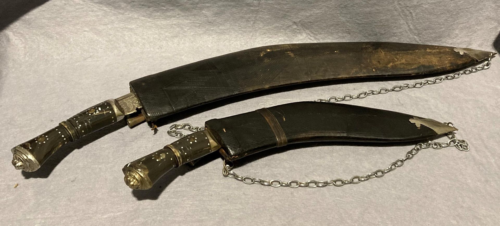 Two assorted sized Kukri knives with lions head and horn handles,