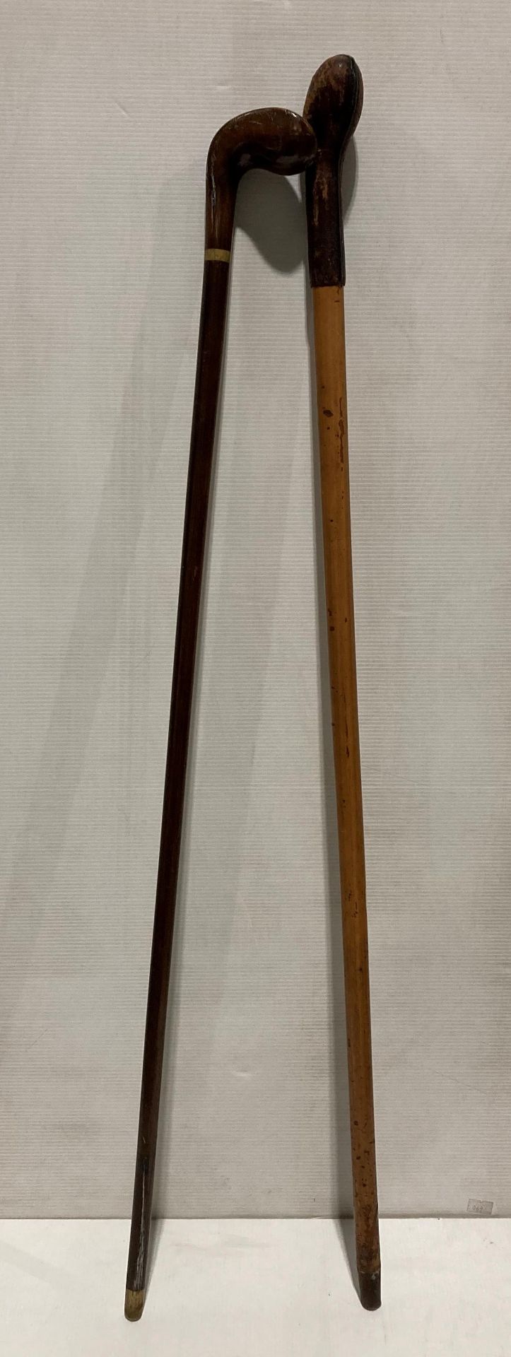Two wooden walking sticks - one with leather bound handle (93cm long) and a right hand walking