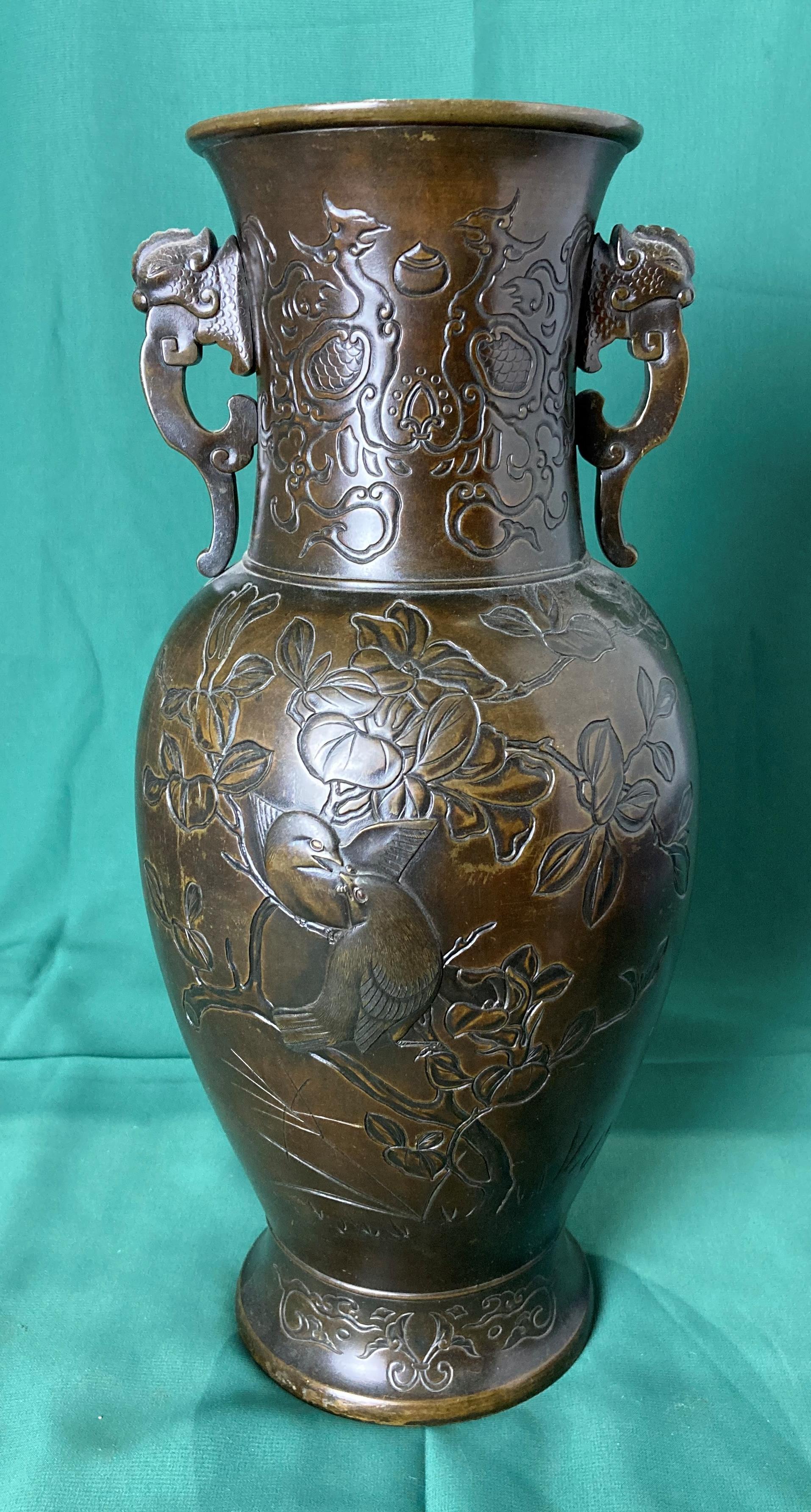A bronze Oriental vase with engraved details of birds and floral designs and lugged handles, 34.