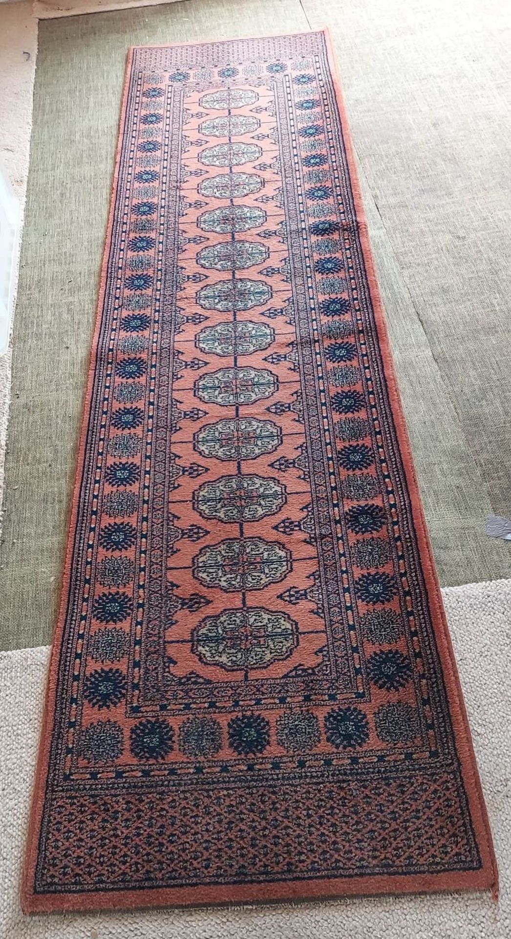 A pink and blue patterned oriental runner,