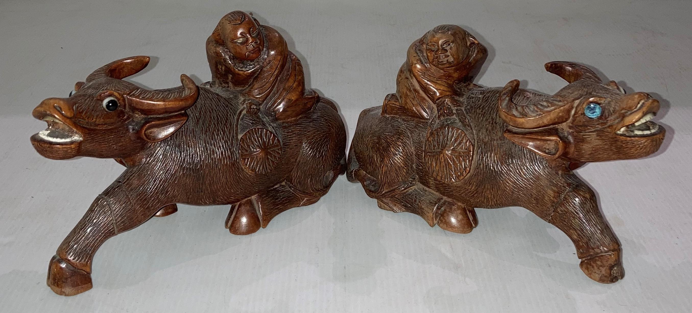 Pair of wooden hand-carved Oriental water buffalo with figures seated, approximately 10.