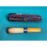 A cigarette holder with possibly amber end and silver collar in original leather case (saleroom