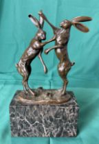 A bronze sculpture of two boxing hares on marble base by Mario Nick,