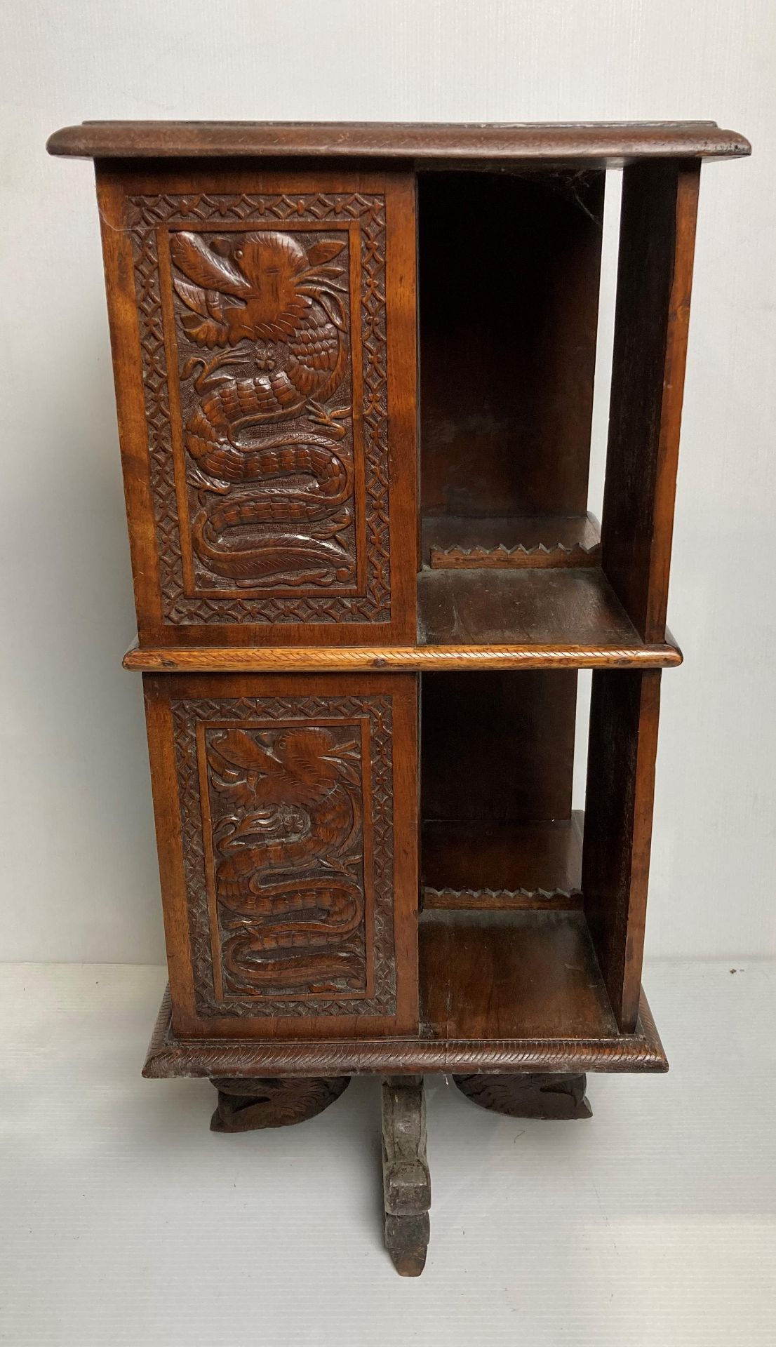 A Oriental wooden hand-carved revolving bookcase with dragons to panels and four dragon feet,