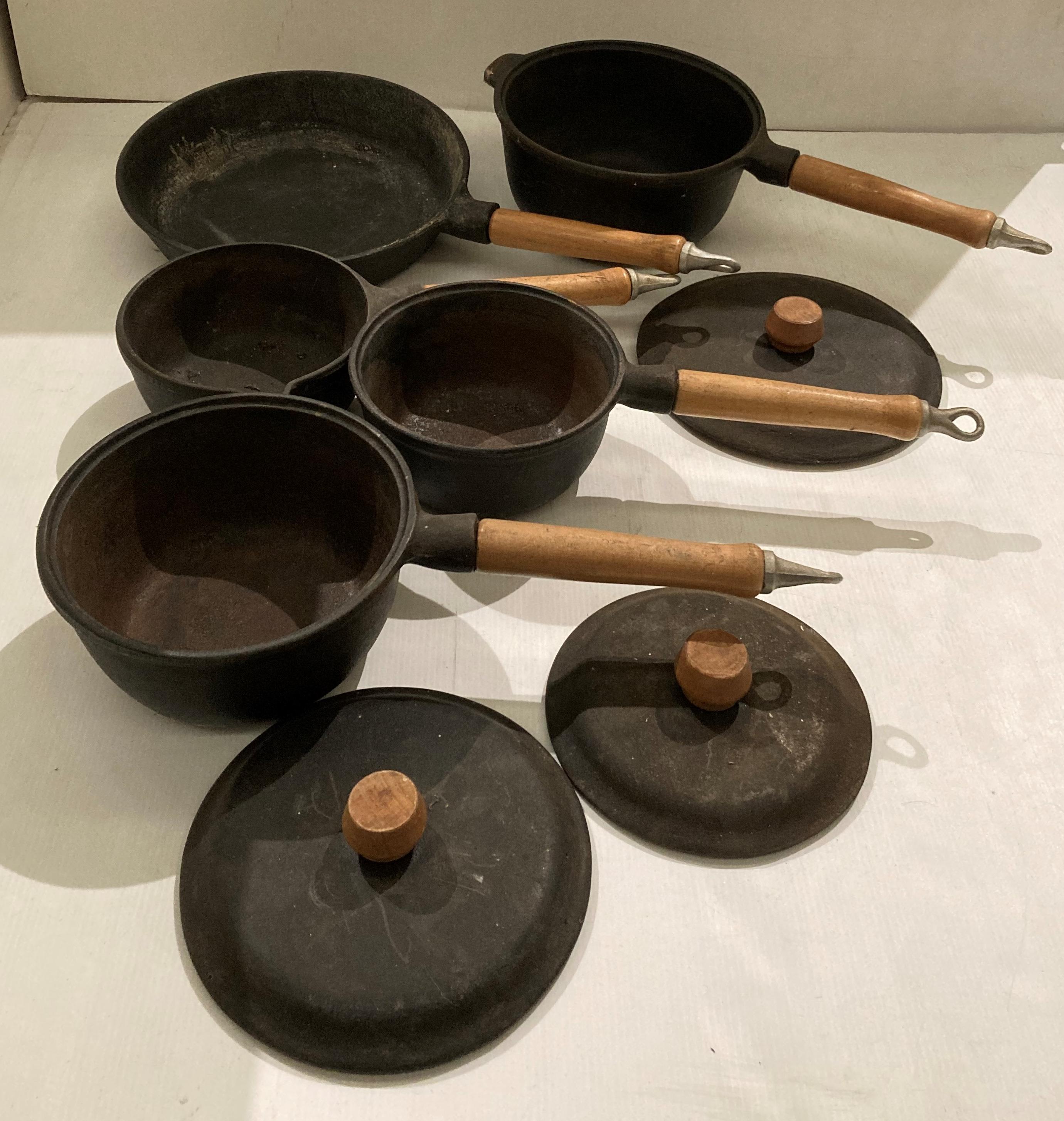 Five-piece cast iron pan set with wooden handles (saleroom location: S1QA06)