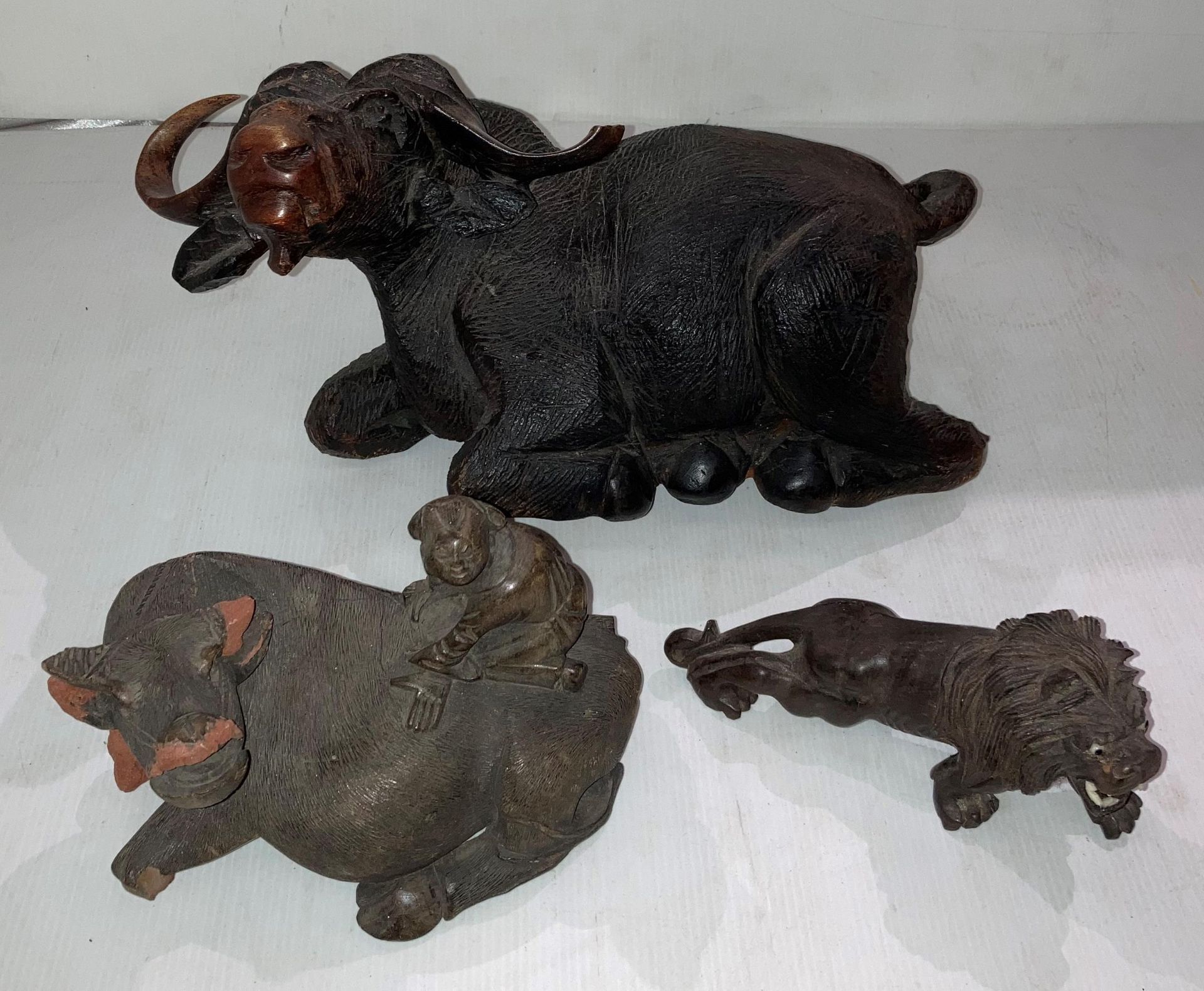 A large hand-carved wooden laid down water buffalo (damage to right horn) (39cm x 20cm high),