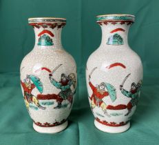 A pair of Oriental vases decorated with fighting warriors in a crackle glaze and stamp to base,