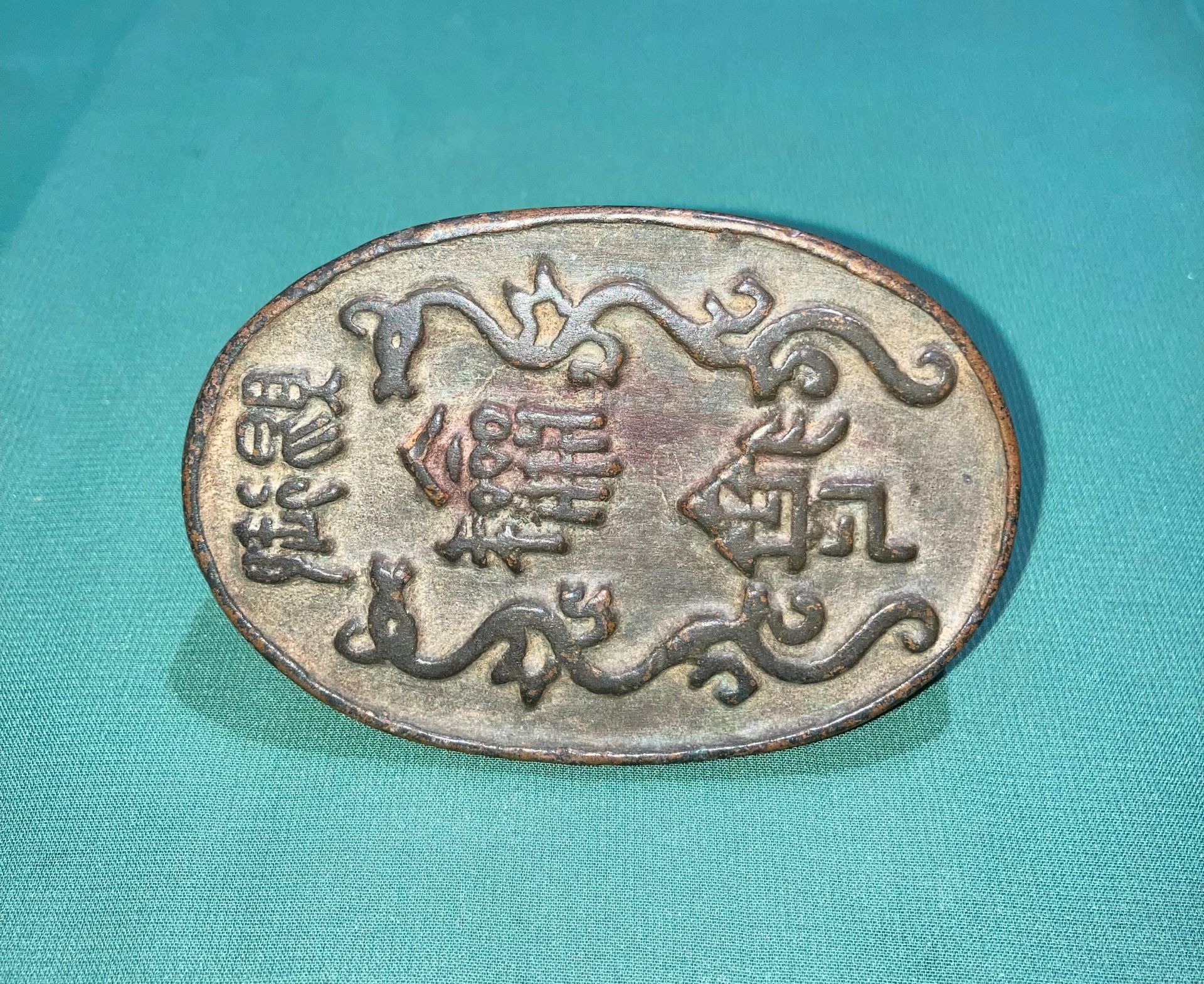 An antique oval bronze Oriental stamp/wax seal with engraved writing to top and dragons to base, 8.