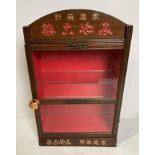 A Japanese mahogany glass-fronted cabinet with engraved writing and metal plaques - possibly for