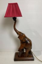 A wooden hand-carved elephant table lamp with raised trunk (missing tusks),