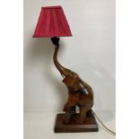 A wooden hand-carved elephant table lamp with raised trunk (missing tusks),