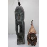 Two wooden hand-carved African figurines including a sitting man with hat and shell decorations