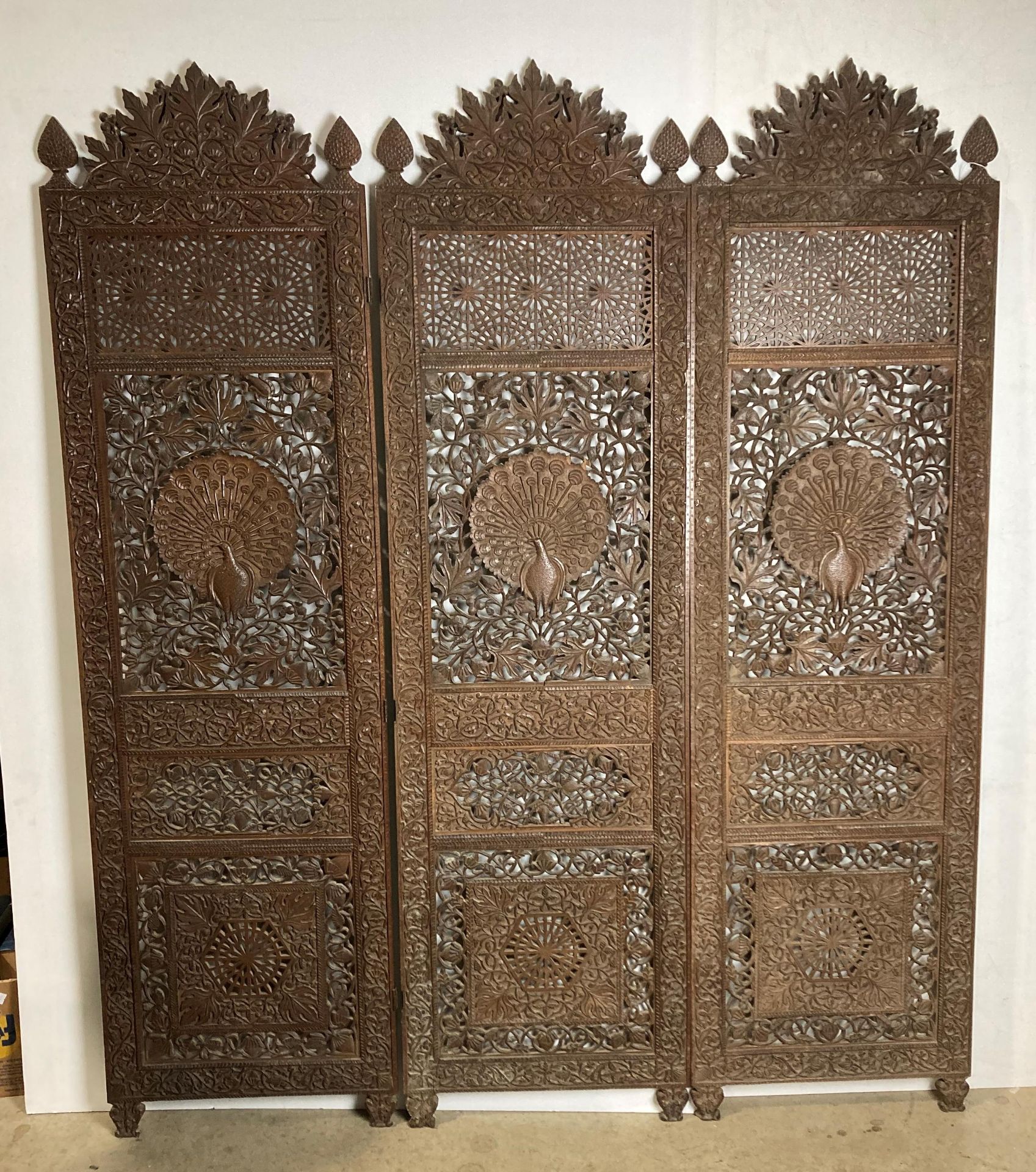An Asian wooden hand-carved three-panel display screen with detailed peacock to each panel and