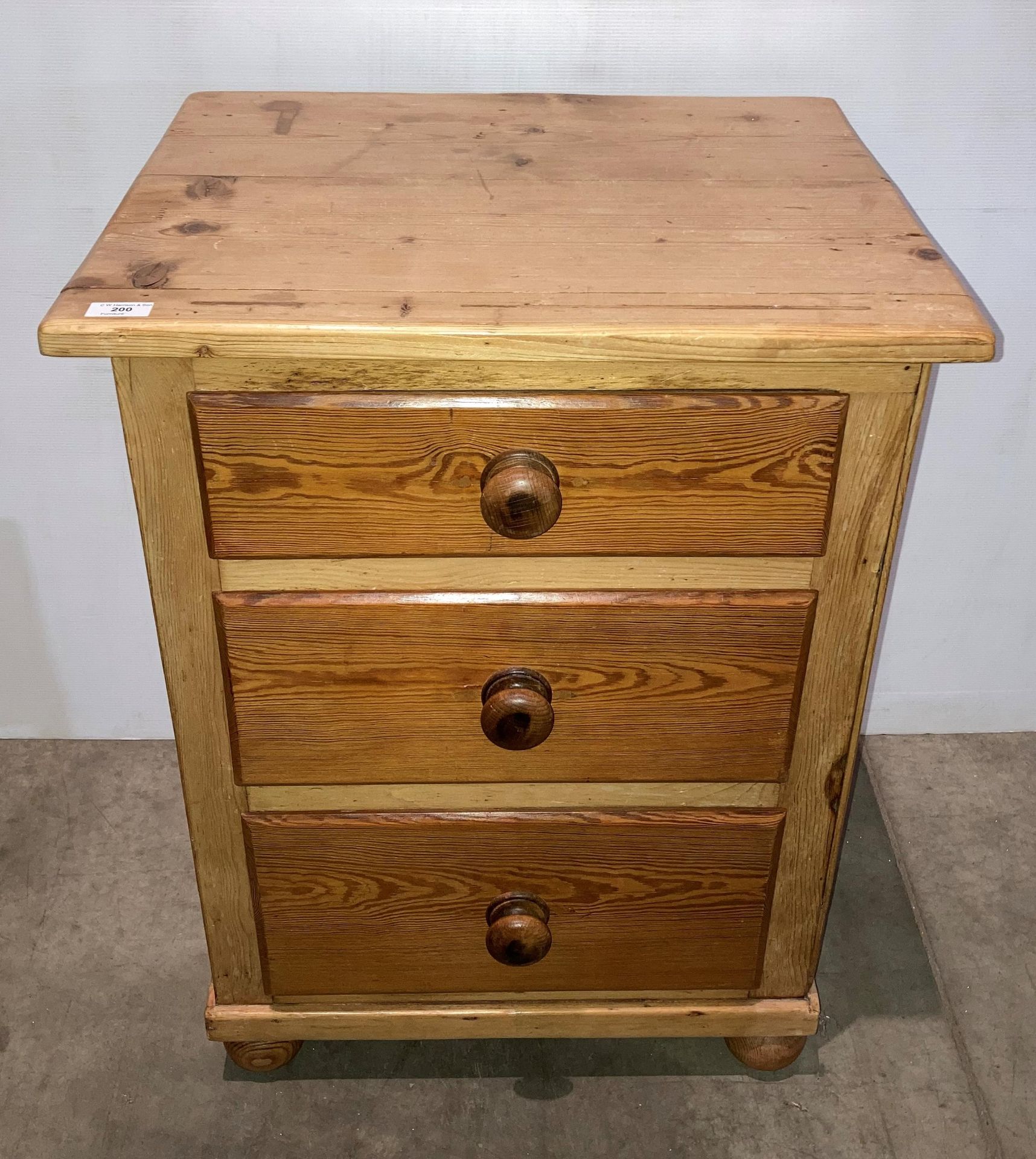 A stripped pine large three-drawer bedside unit,