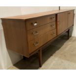 A Mid-Century 'Beautility' teak sideboard with pull-out drinks cabinet revealing six shelves,