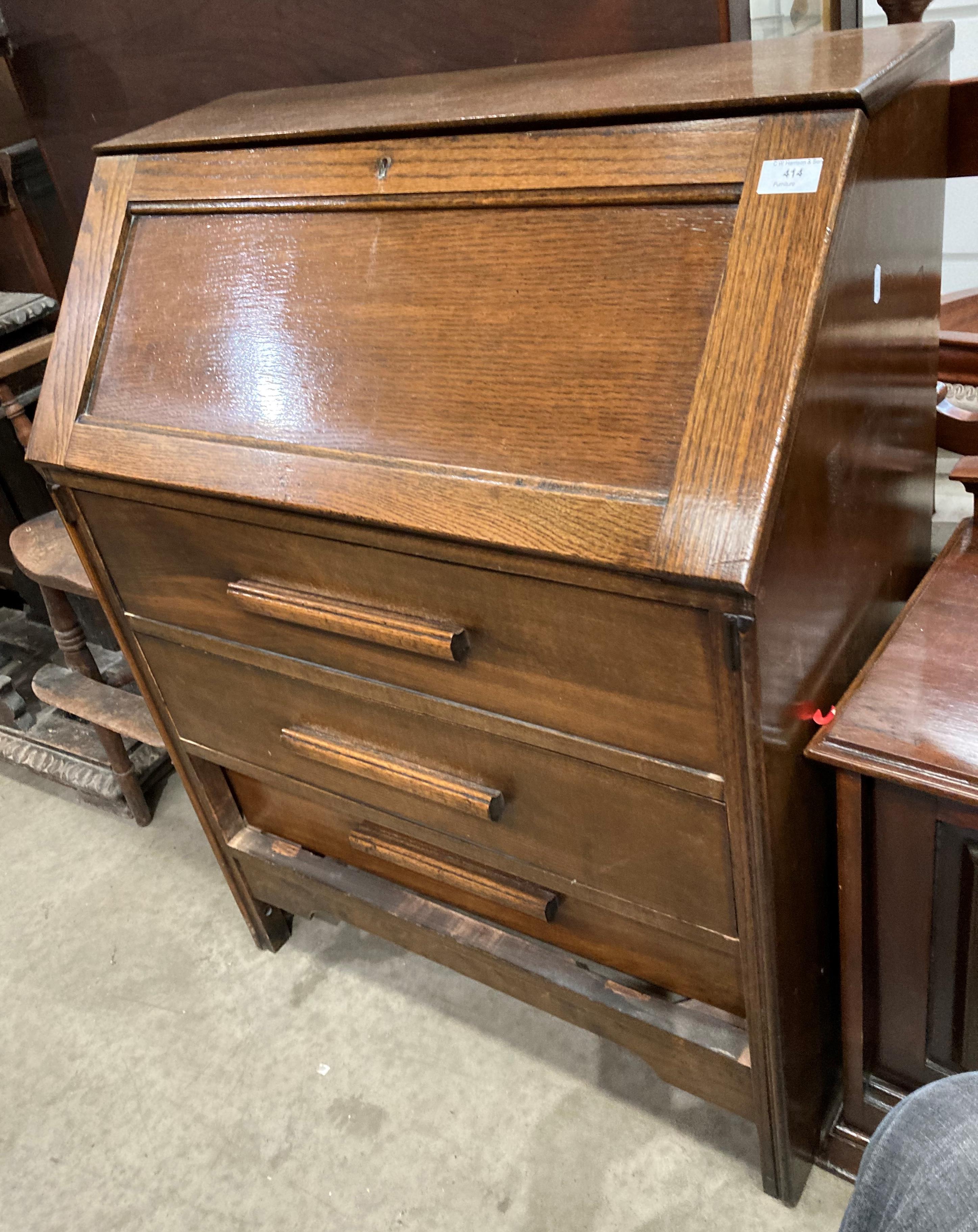 An oak bureau with fall-flap over three drawers,