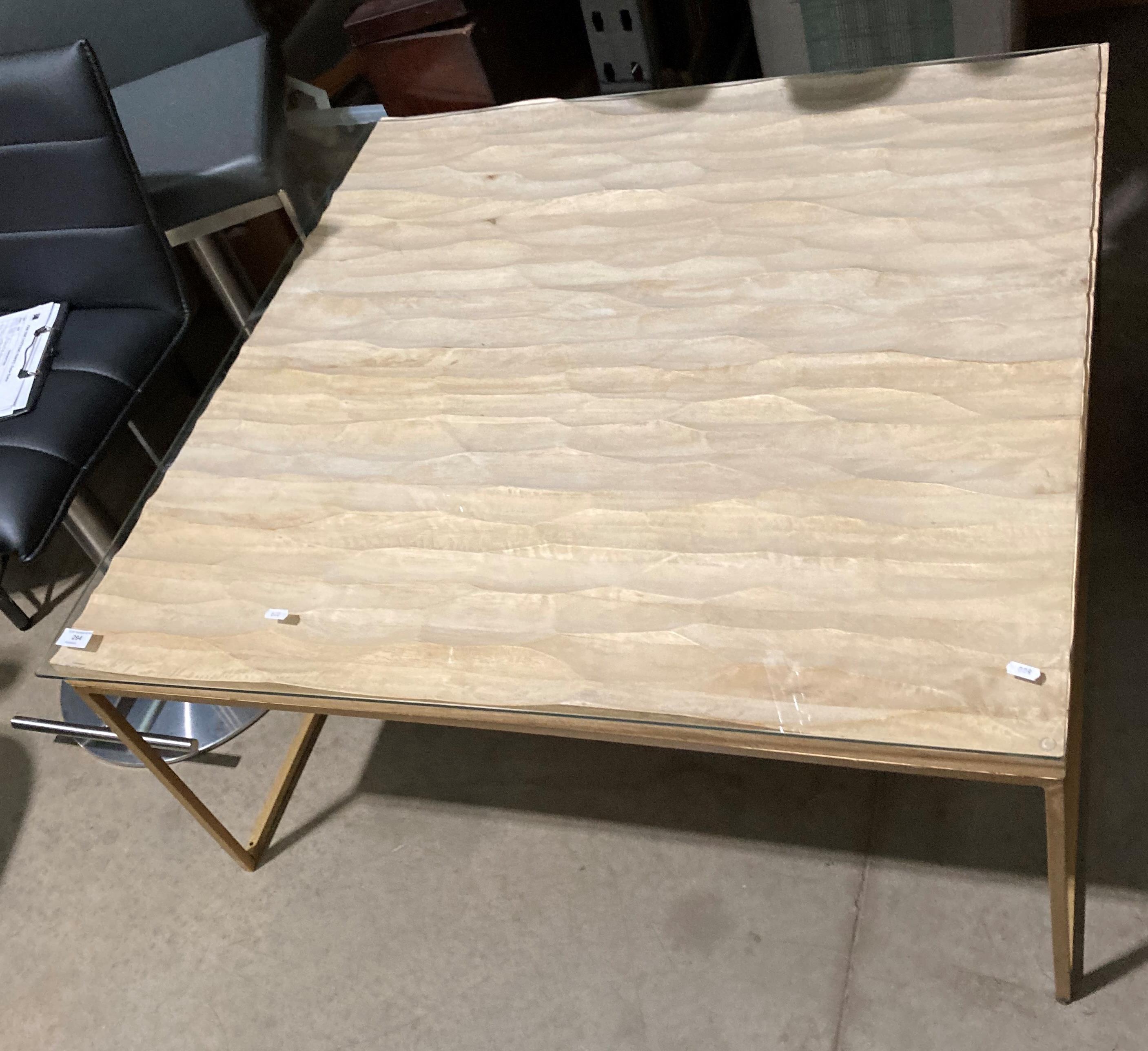 A metal framed coffee table with uneven wood top and glass protective cover,