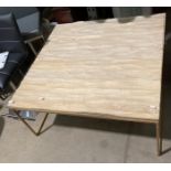 A metal framed coffee table with uneven wood top and glass protective cover,