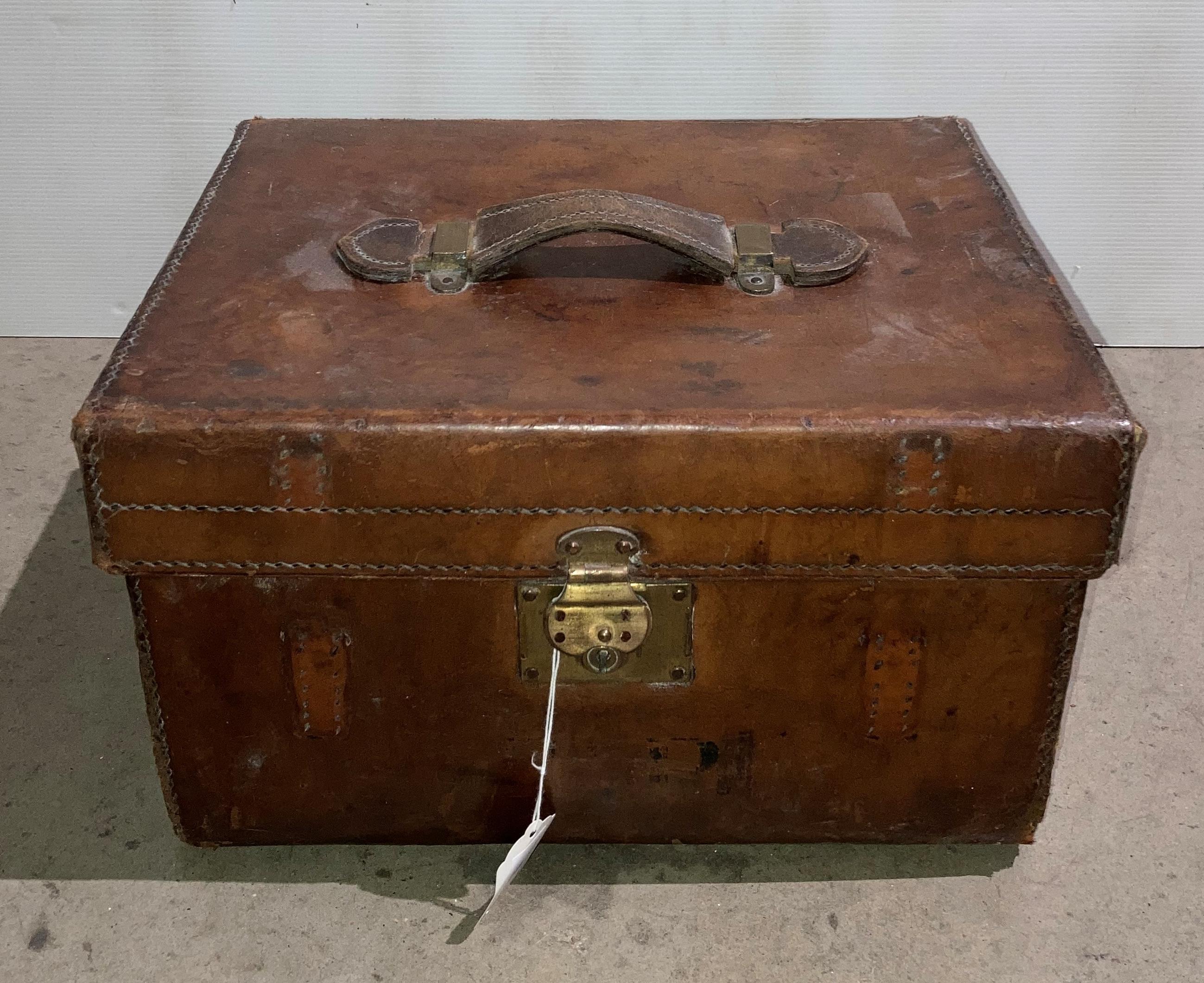 A brown leather box luggage case with red lining,