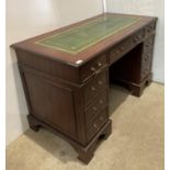 A mahogany twin pedestal desk with green tooled leather top with six small drawers,