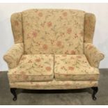 High wing-back two-seater settee with floral upholstery,