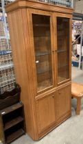 A William Lawrence light wood finish wall unit with two glass doors and three glass shelves over
