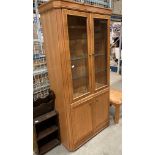 A William Lawrence light wood finish wall unit with two glass doors and three glass shelves over