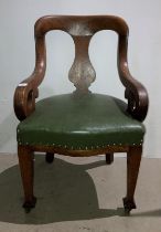 An oak armchair with green leather-finish seat and open scroll arms (saleroom location: S2 QA02)