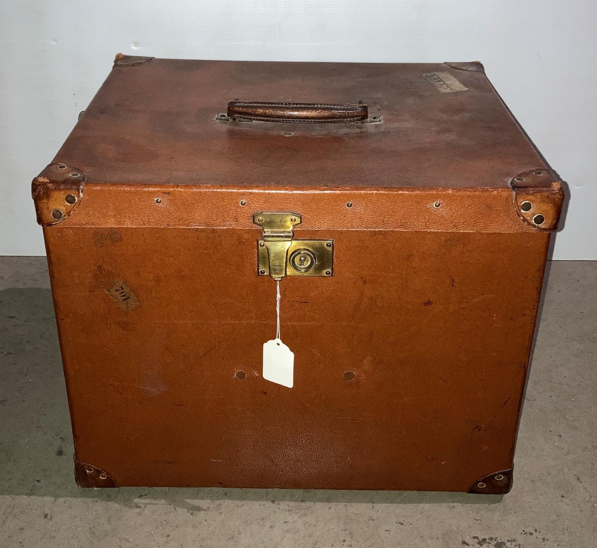 A brown leather-finish luggage case with wood and metal runners to base with initials AAM to side