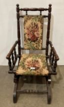 A vintage mahogany children's rocking chair with floral fabric and turned supports,