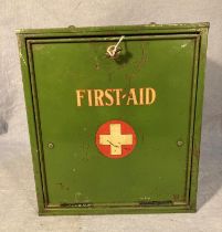 A green metal First Aid cabinet with drop-down front and internal shelf, 24cm x 26cm x 14.