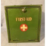 A green metal First Aid cabinet with drop-down front and internal shelf, 24cm x 26cm x 14.