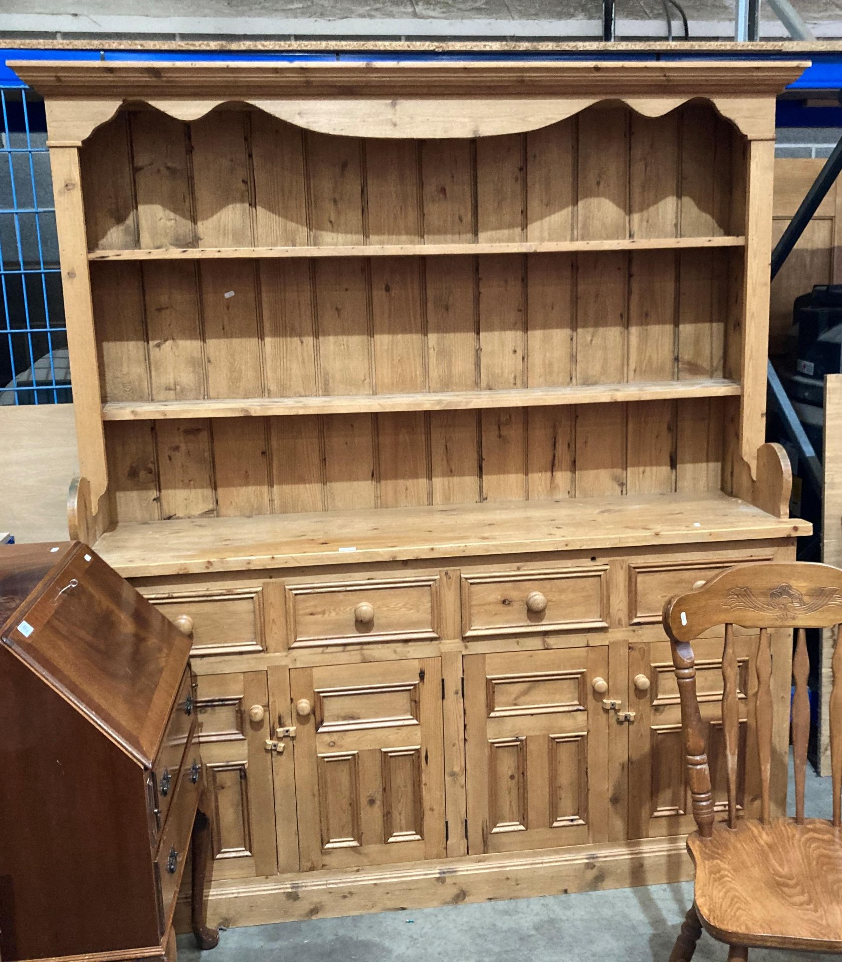 A pine dresser with two shelves over four-drawer, four-door base,