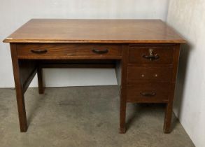 An oak four-drawer desk with central long drawer, three short drawers and a right-hand pedestal,