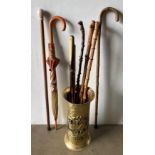 A thin brass umbrella stand and five assorted walking sticks,